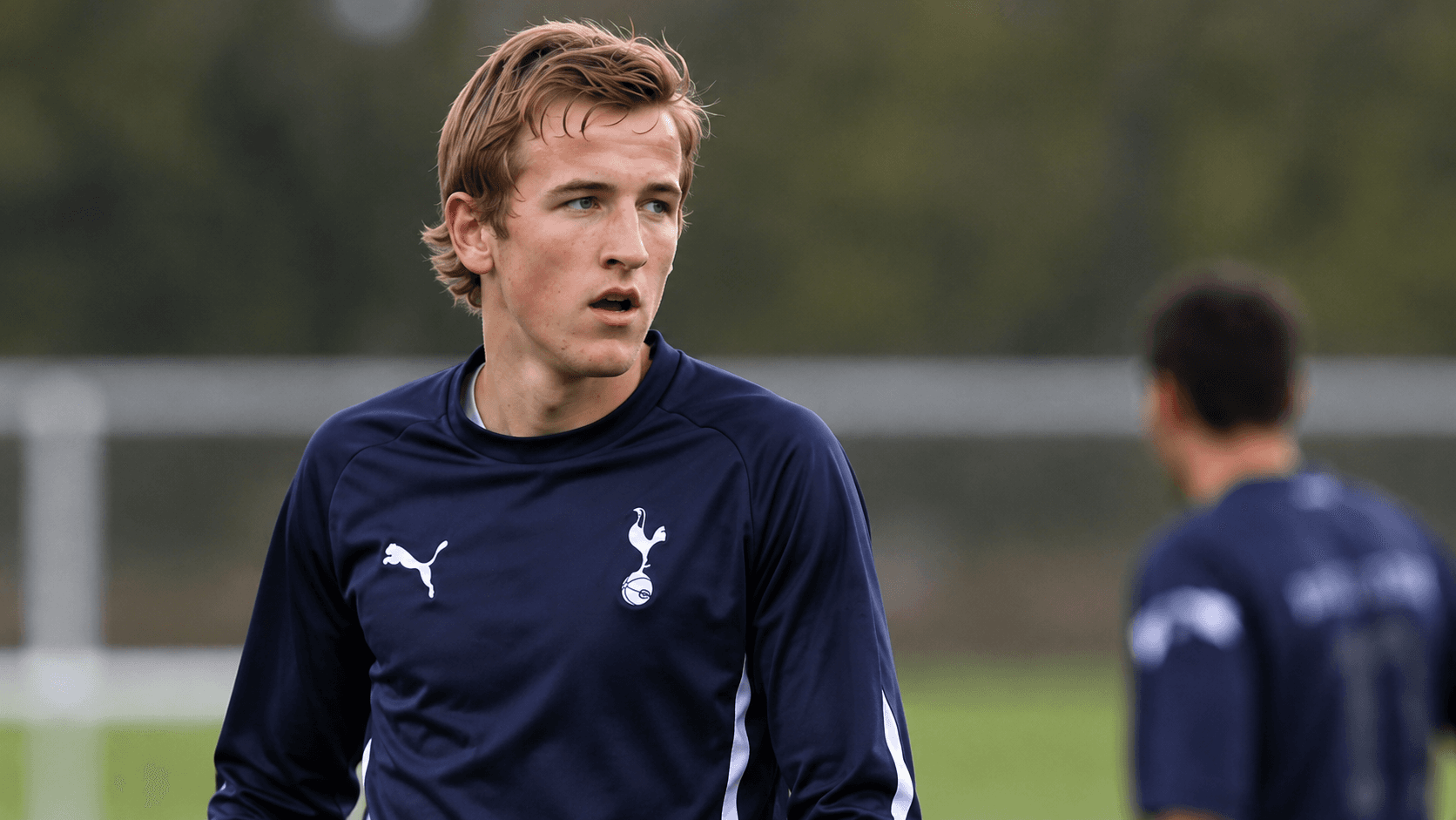 Illustration: a young Harry Kane in a navy Tottenham training top, looking across a training pitch