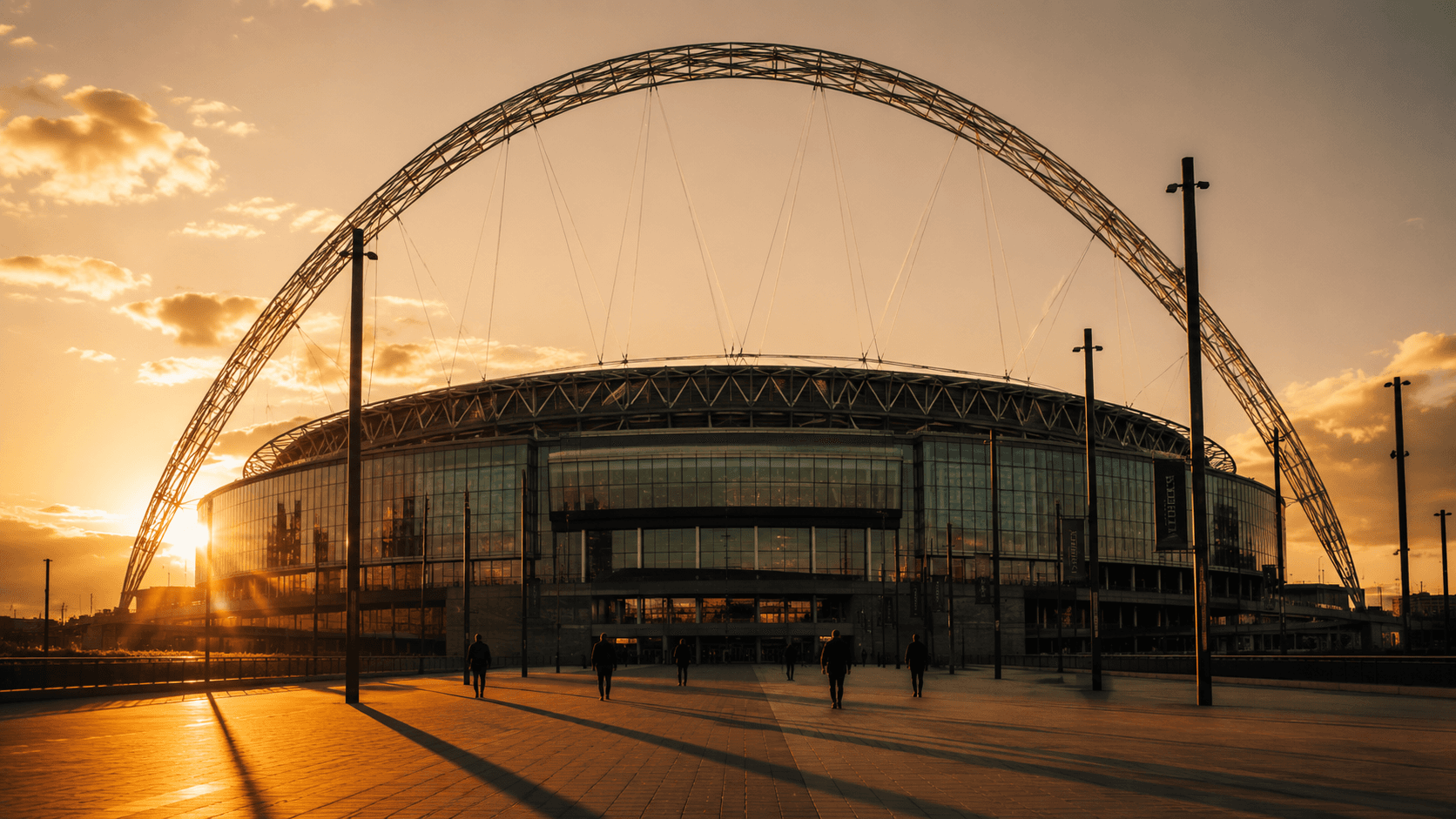 Wembley at golden hour, the arch casting long shadows across an empty forecourt