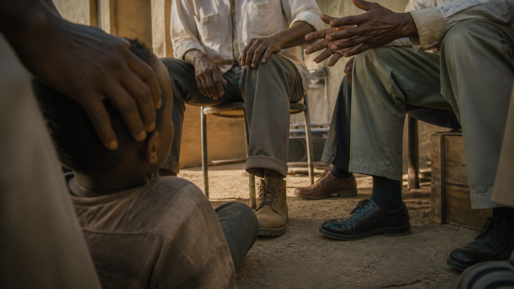 A boy at knee height among the men's legs, a hand resting on the top of his head β the vantage point this whole piece is written from