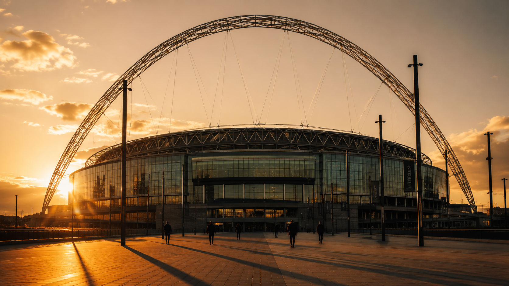 Wembley at golden hour, the arch casting long shadows across an empty forecourt